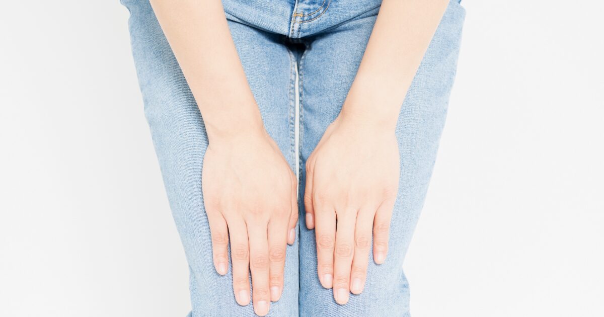 デニムを履いた女性が膝に手を添えている様子
