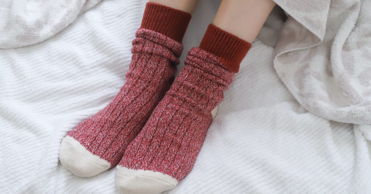 赤い靴下を履いた足元と白い毛布