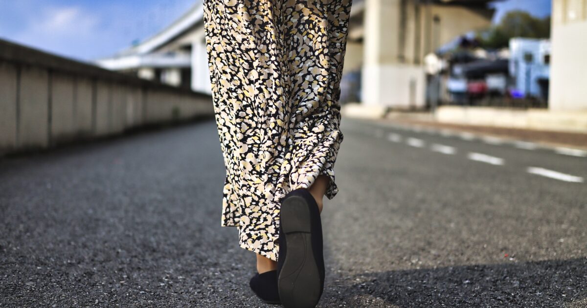 花柄ワンピースとバレエシューズで歩く女性の後ろ姿