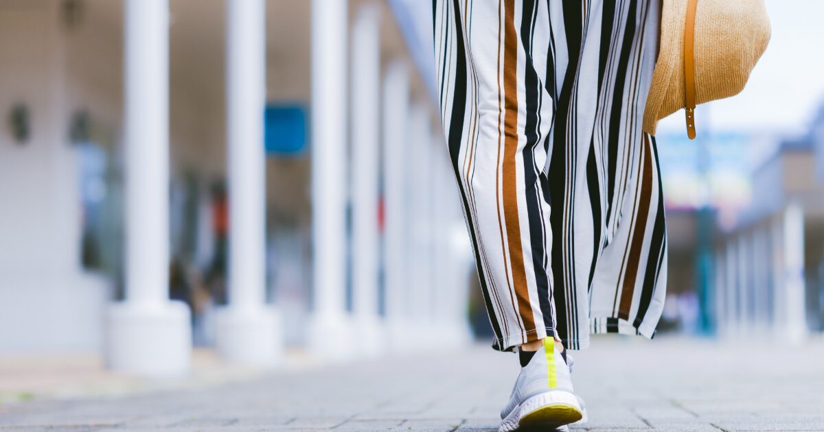 ストライプパンツとスニーカーで歩く女性の足元