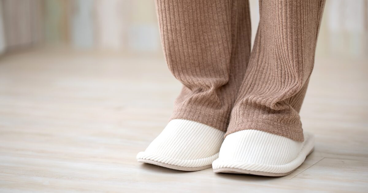 ルームウェアと白いスリッパを履いた足元