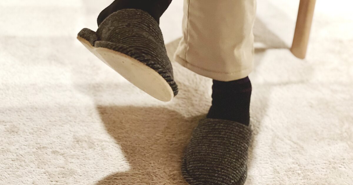 スリッパを履いて足を上げる女性の足元