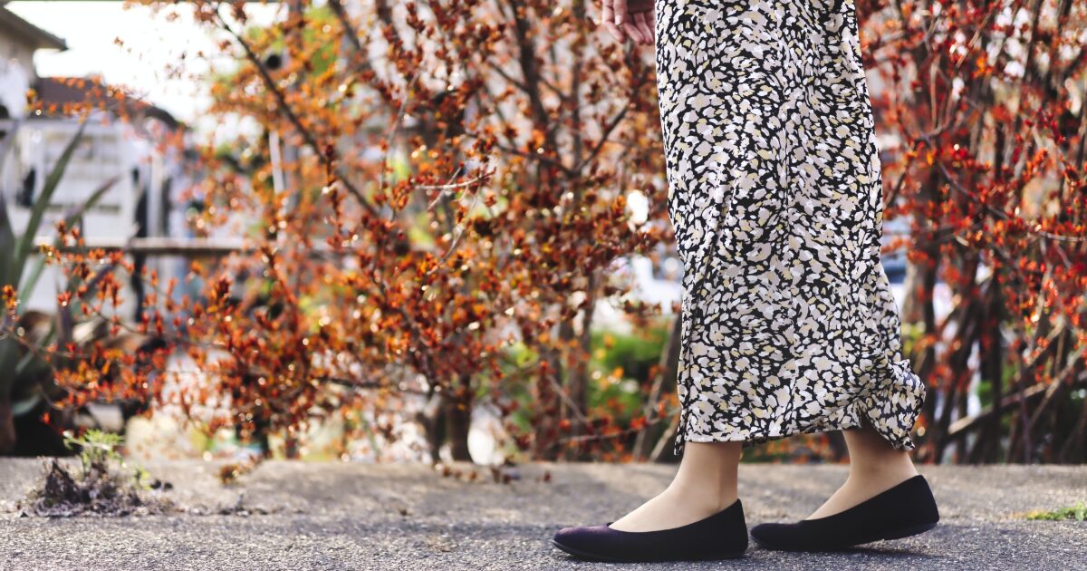 秋の風景と花柄スカートの女性の足元