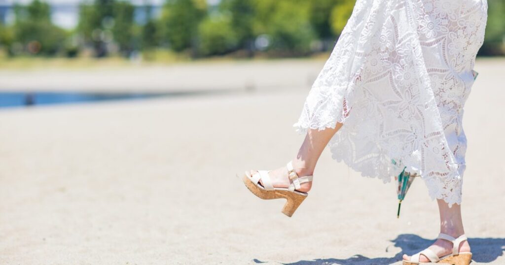 白いレースワンピースとサンダルの女性の足元