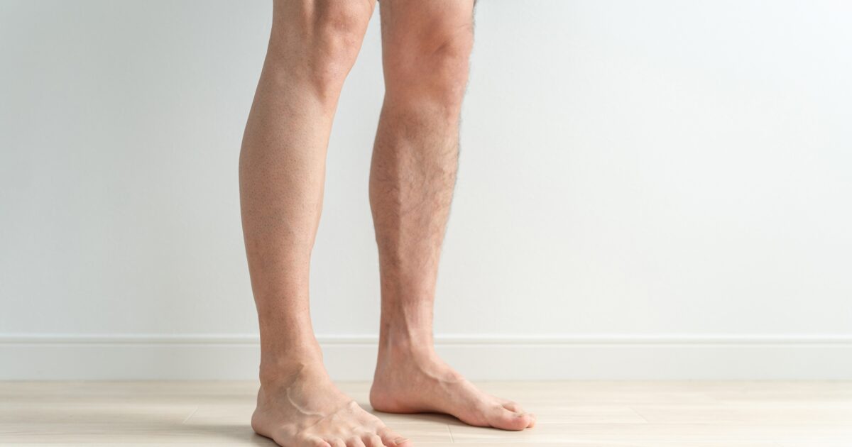 室内で立っている男性の裸足の脚