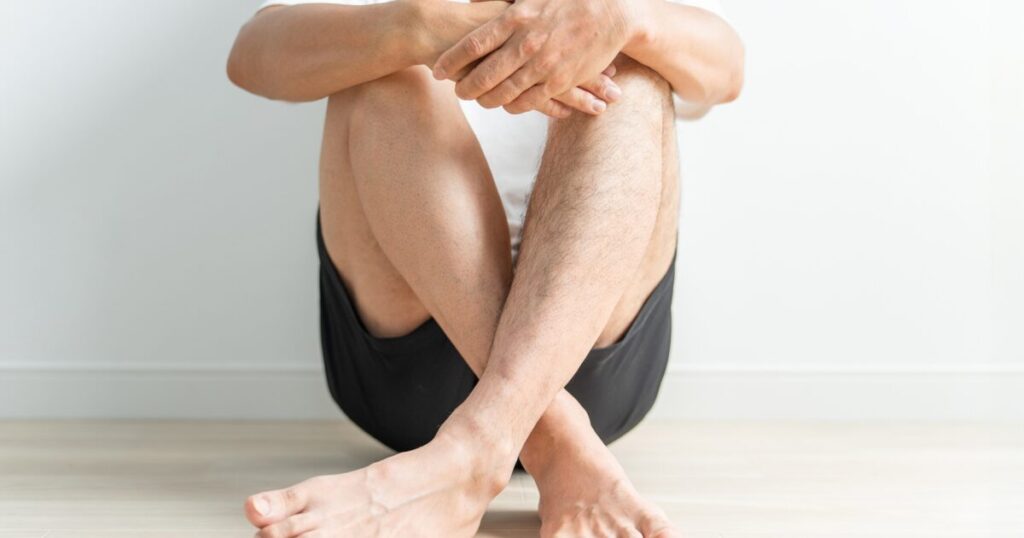 室内で座って足を組む短パン姿の男性