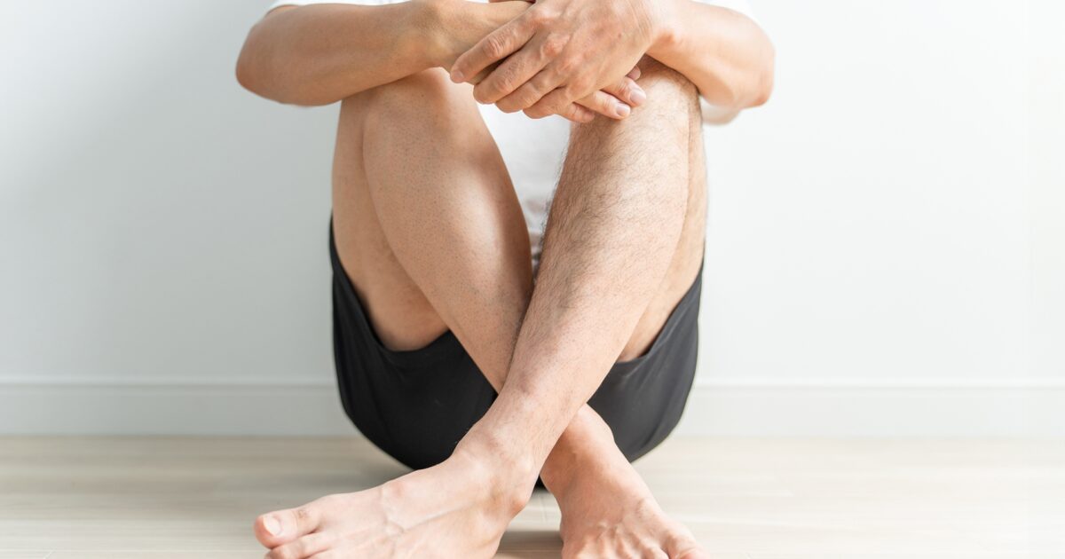 室内で座って足を組む短パン姿の男性