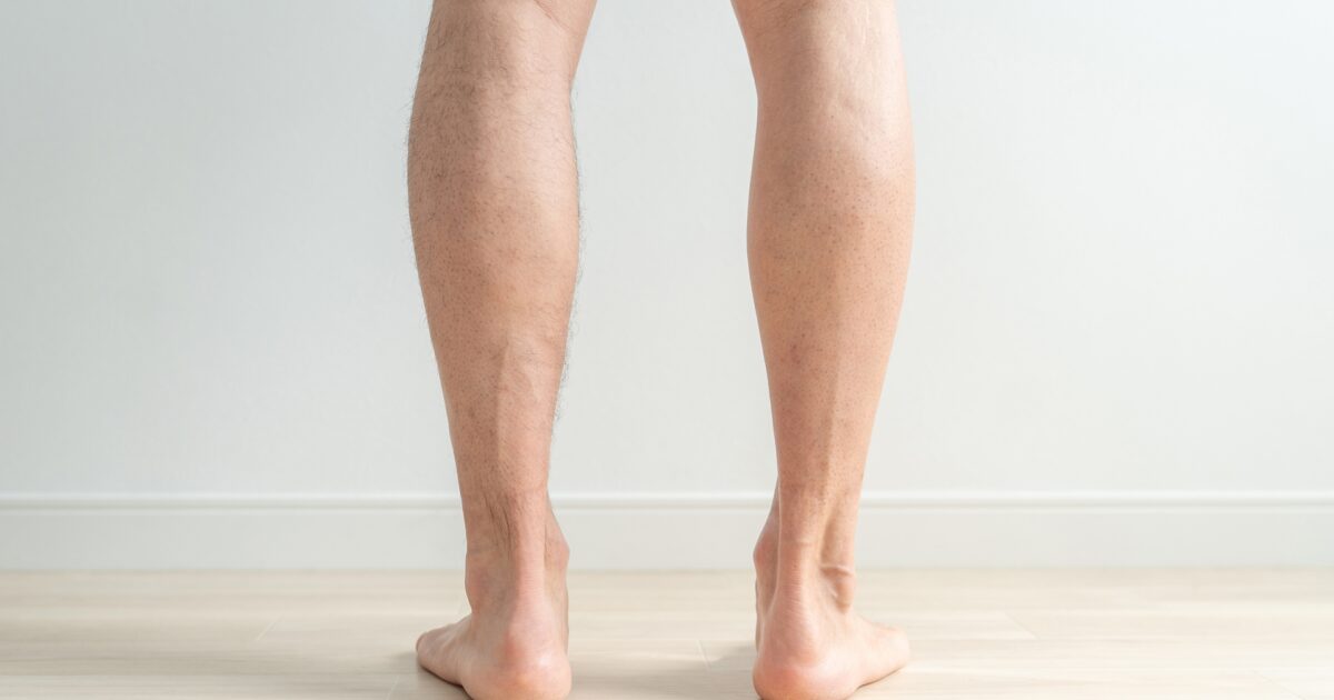 室内で立っている男性のふくらはぎの後ろ姿