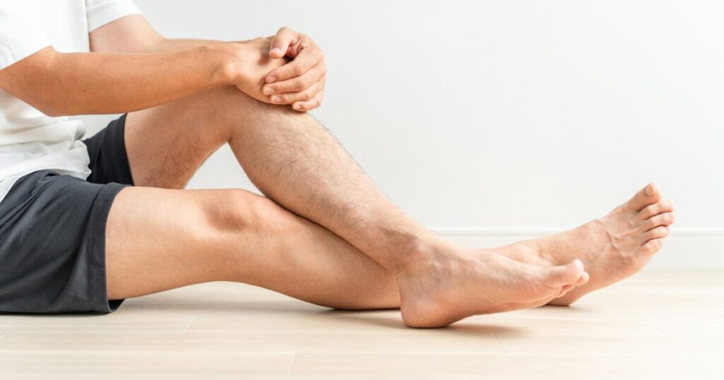 床に座って膝を抱える短パン姿の男性