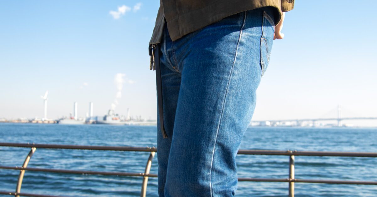デニムジーンズを履いた男性が海辺に立つ様子