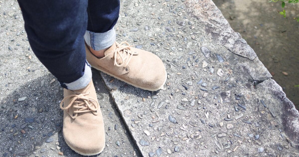 ロールアップジーンズとベージュのスエードシューズの足元