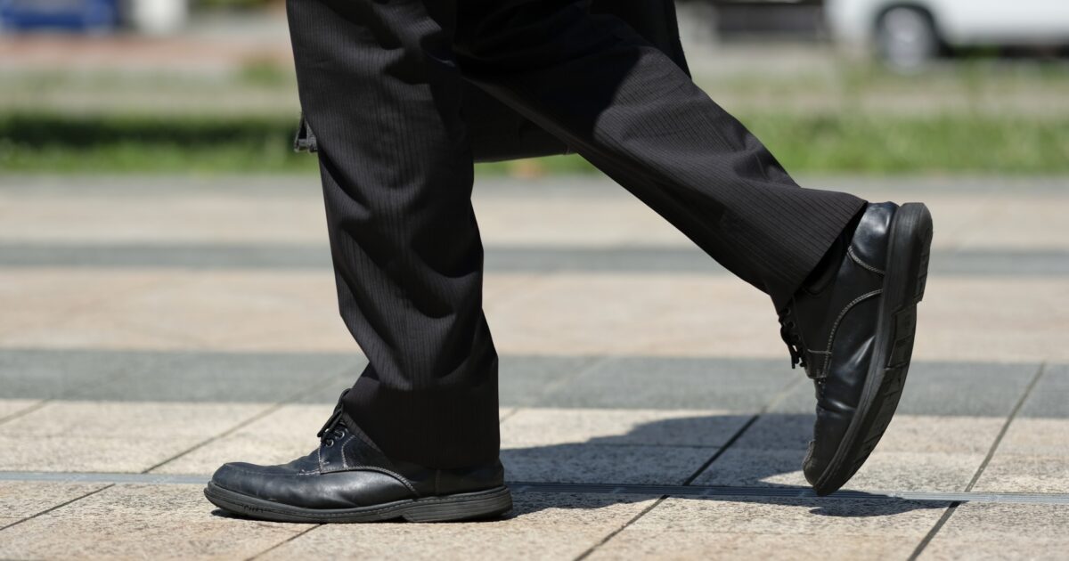 黒いスーツと革靴で歩く男性の足元