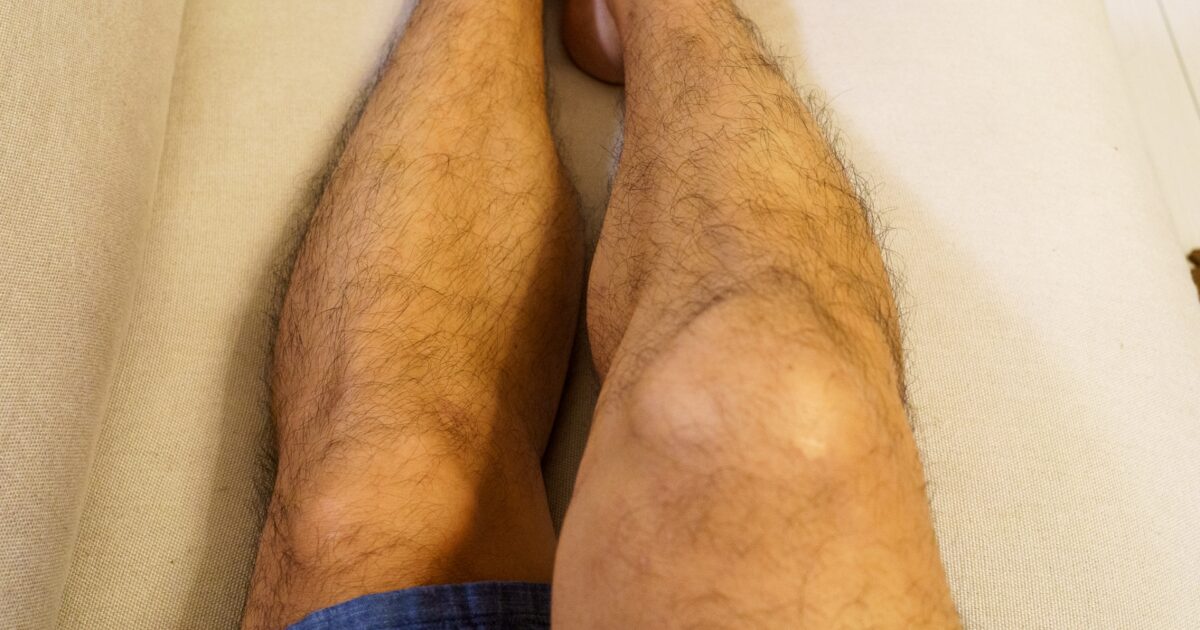 ソファに寝転ぶ短パン姿の男性の脚