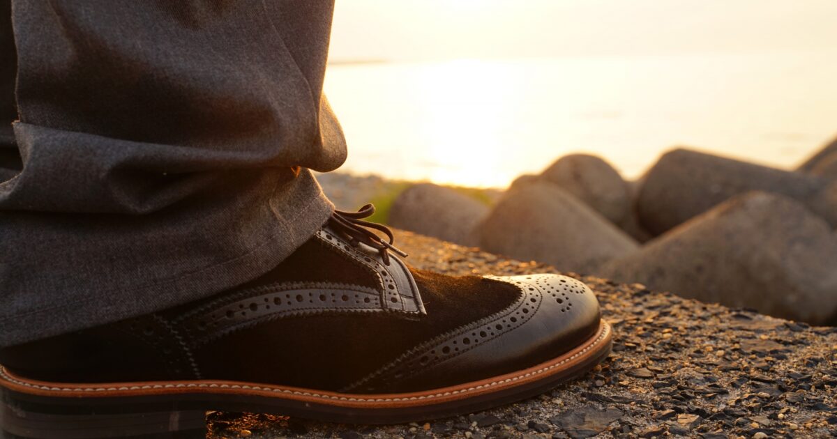 夕日を背景に革靴を履いた人物の足元