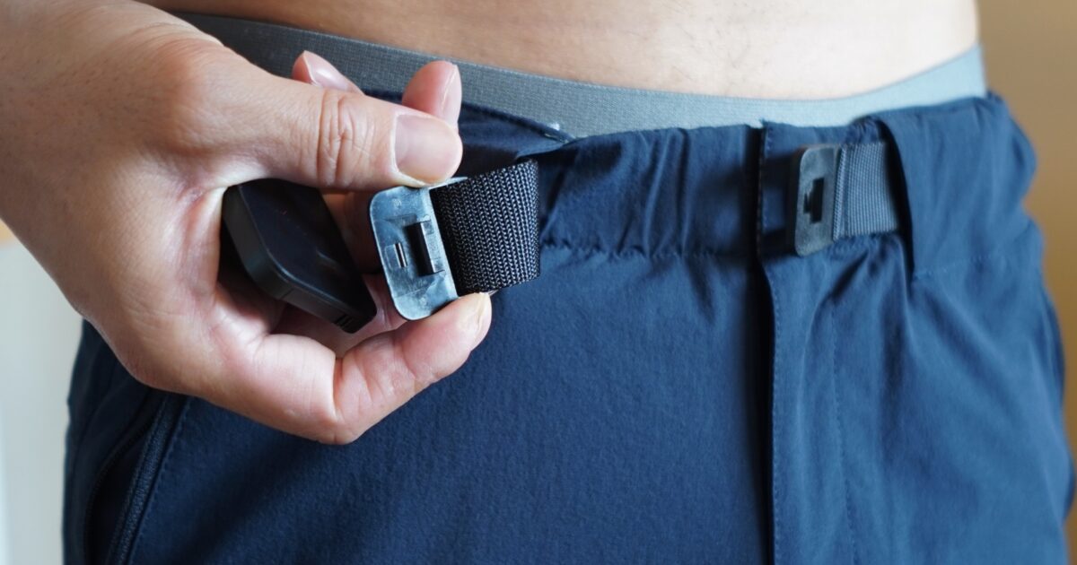 黒いナイロンパンツのウエストを調整する手元のクローズアップ